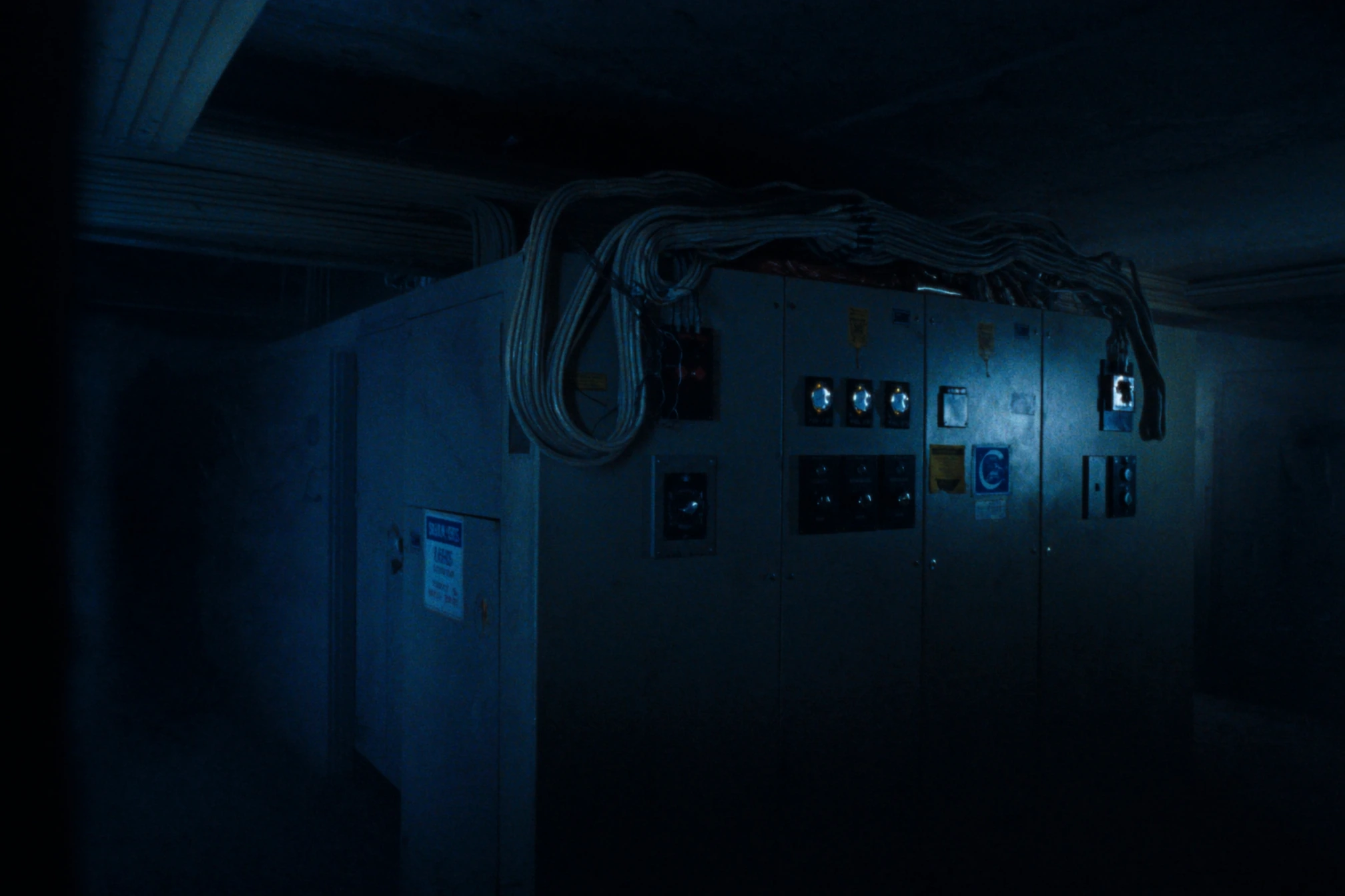 Tableros de switchgear eléctrico de baja tensión en su sala, con mazos de cable y manómetros, en penumbra